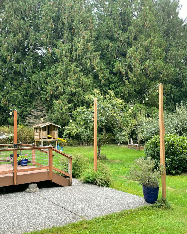 The wood deck and the gravel seating area beside it, with a blue planter, low fencing and the playhouse beyond.